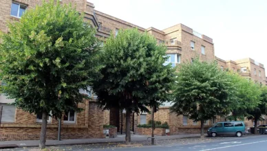Façade en brique d’un immeuble collectif d’habitation bordée d’arbres, rue Libergier à Reims